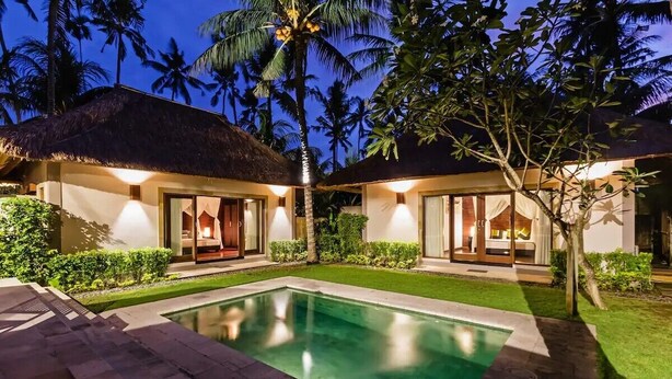 Een resort met twee villa's, een zwembad en een verzorgd gazon.