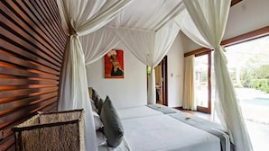 Een slaapkamer met een hemelbed, een schilderij aan de muur en uitzicht op het groen.