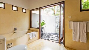 Een badkamer met een bad, toilet en een groot raam.