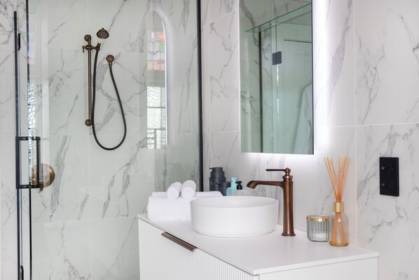 Un bagno moderno con doccia vetro, lavandino bianco e uno specchio grande.