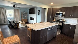 Una cocina moderna con gabinetes de madera oscura, electrodomésticos de acero inoxidable y una isla de mármol.