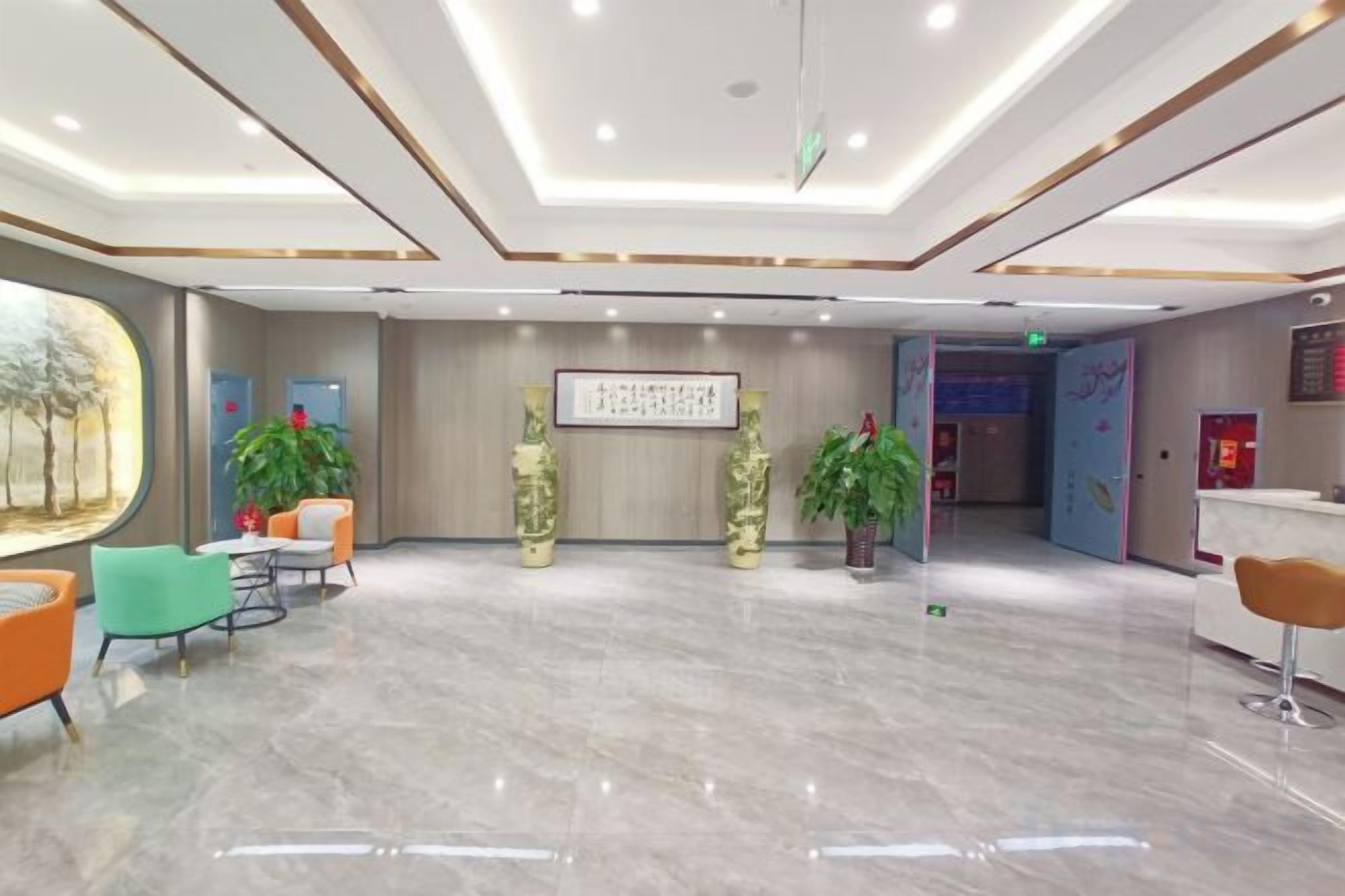 A hotel lobby with a reception desk, seating area, and decorative plants.