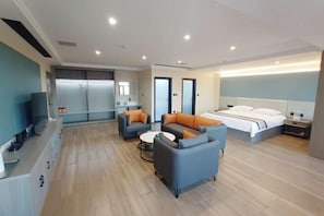 A modern hotel room with a sofa set, a bed, a small table, and a TV. - Tianma Hotel (Hami)