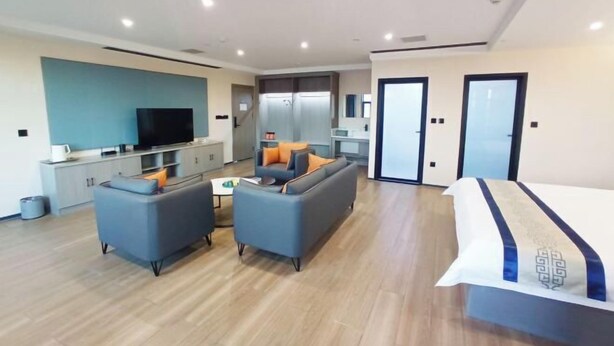 Une chambre d’hôtel moderne équipée d’un canapé, d’une télévision, d’un lit et d’une kitchenette.