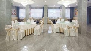 Un vaste espace dédié à la salle à manger, avec des tables et des chaises rondes, un sol en marbre et des œuvres d’art décoratives sur les murs.