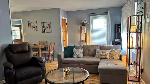 Una sala de estar con sofá, sillón, reposapiés y mesa de centro.