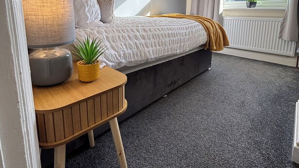 Un dormitorio con cama, mesita de noche, lámpara y ventana con vistas.