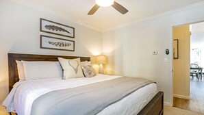 A neatly made bed with a wooden headboard, a bedside lamp, and two framed wall art pieces.