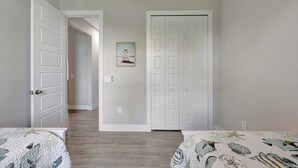 Ein Schlafzimmer mit zwei Betten, einer weißen Tür und einem Flur, der in einen anderen Raum führt.