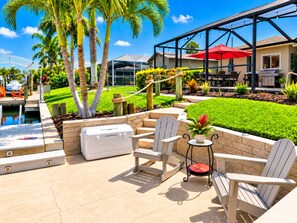 A patio area with outdoor seating, a pool, and a house in the background.