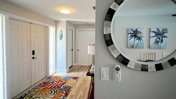 Um corredor com tapete estampado, portas brancas, luminária no teto e espelho com moldura decorativa na parede.