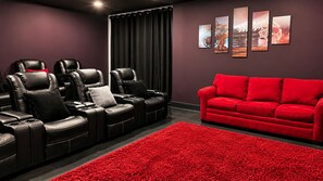 Een bioscoopzaal met zwarte leren fauteuils, een rode bank en een roodgekleurd vloerkleed.