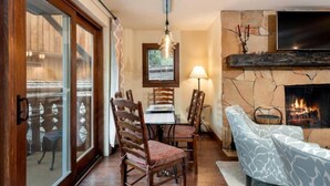 A cozy living room with a fireplace, wooden furniture, and a large window. - Modern 2 Bedroom Condo at the Base of Vail Mountain Next to Gondola One (Vail)