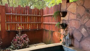 Un espace avec un jacuzzi, agrémenté d’un mur en pierre, d’une clôture en bois et de plantes en pot.