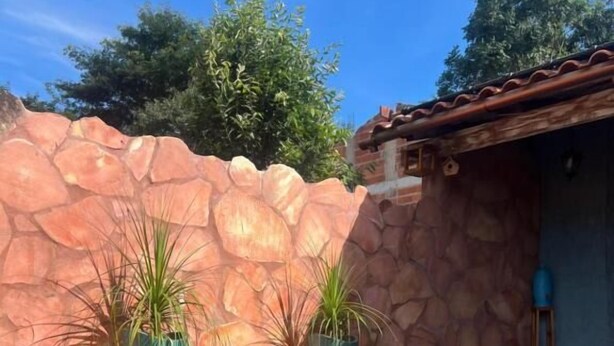 Un coin petit-déjeuner aménagé au bord de la piscine, avec un mur en pierre, des plantes en pot et une vue dégagée sur la piscine.