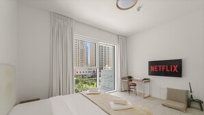 Een moderne hotelkamer met een groot bed, een bureau, een stoel en uitzicht op hoge gebouwen.