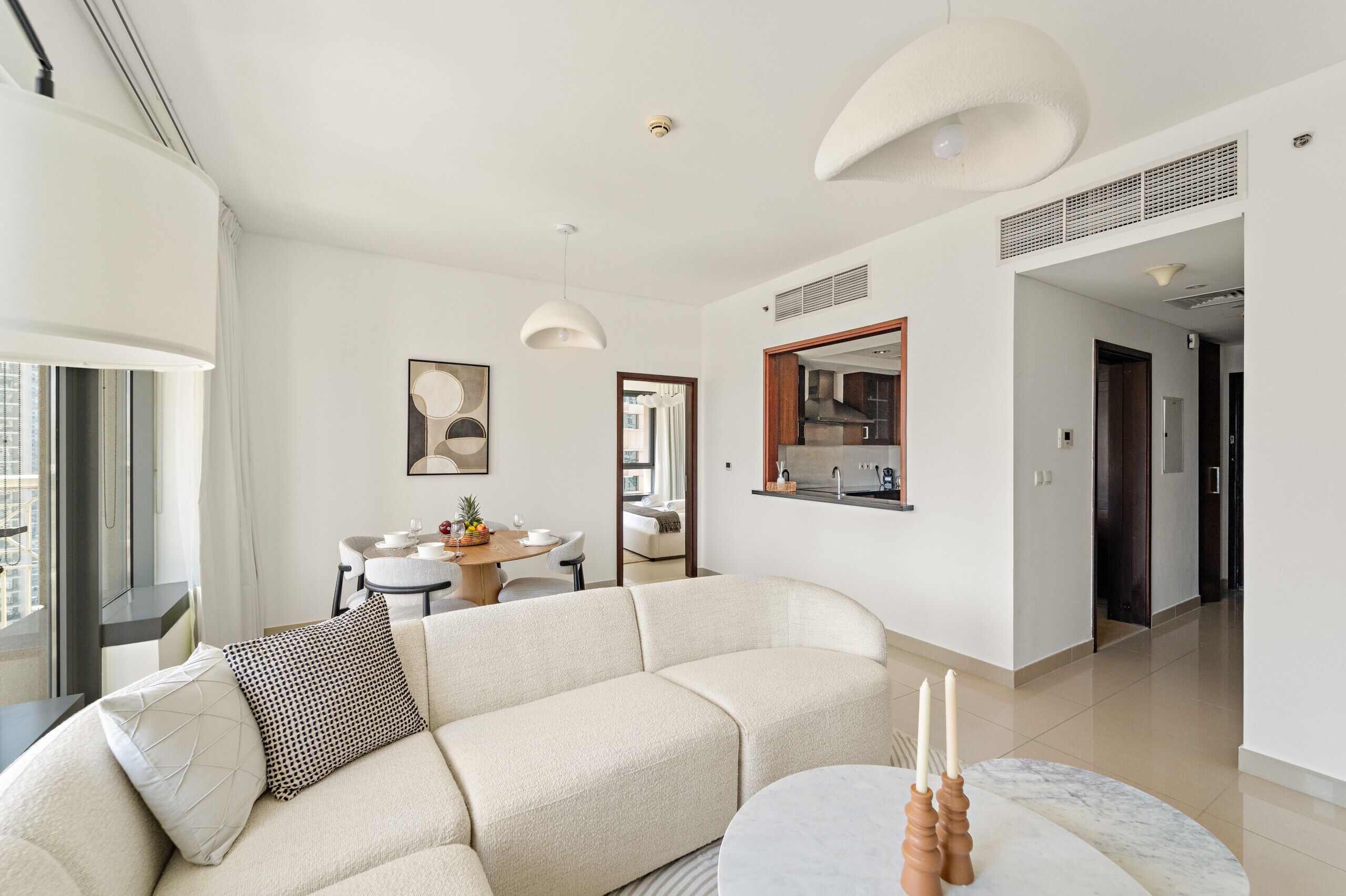 Ein modernes Wohnzimmer mit einer Couch, einem Esstisch mit Stühlen, einer Küchenzeile und Blick auf die Stadt.