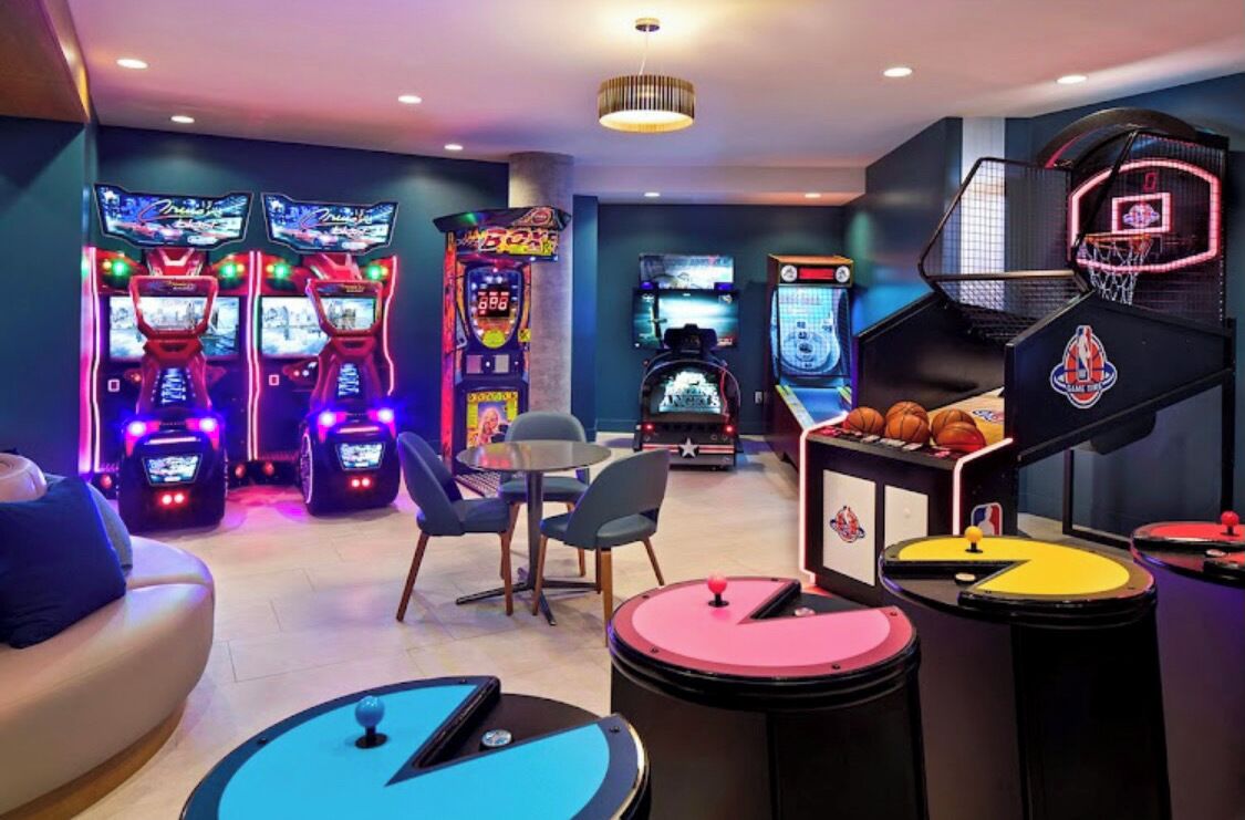 Un'area giochi con cabinati arcade, un canestro da basket e un piccolo tavolo con una palla.