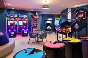 A gaming area with arcade machines, a basketball hoop, and a small table with a ball. - Comic Con! Luxury Views Steps from Gaslamp Quarter Petco Park (San Diego)