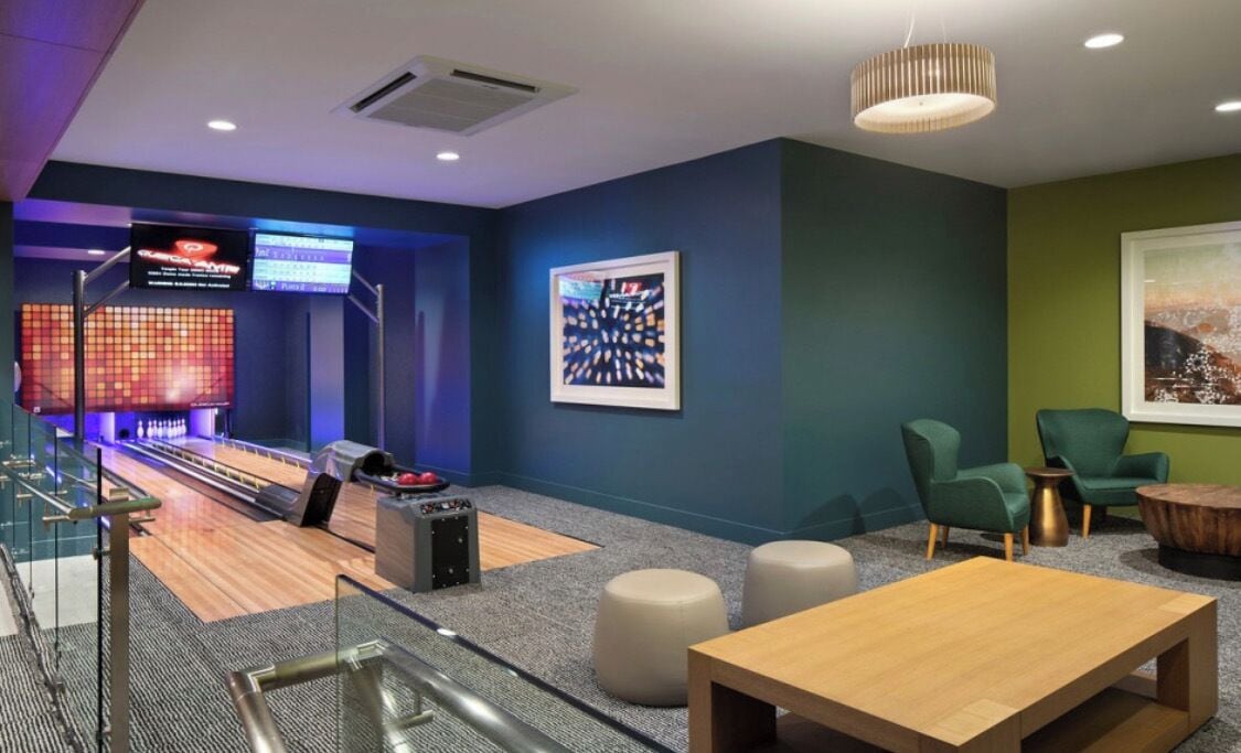 Un área de lounge moderna con bolera, asientos cómodos y una gran obra de arte enmarcada en la pared.