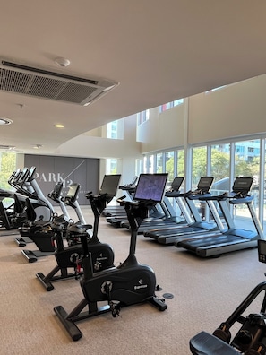 A gym with multiple treadmills and stationary bikes, large windows, and a visible sign that says "PARK". - Comic Con! Luxury Views Steps from Gaslamp Quarter Petco Park (San Diego)
