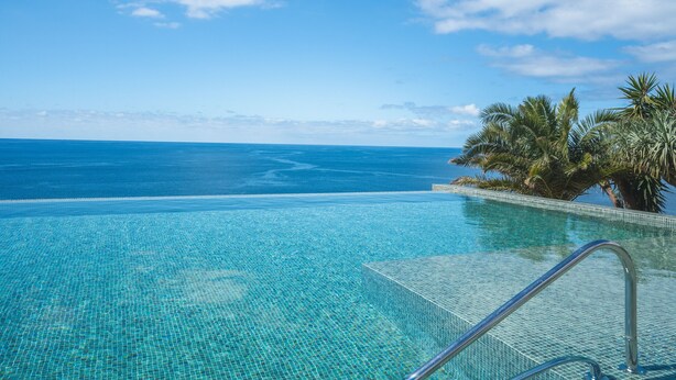 Una piscina infinita con agua azul cristalina y vistas al océano.