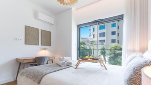 Una habitación de hotel moderna con una cama grande, un escritorio y un balcón con vistas a la ciudad.