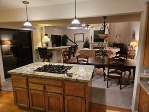 A kitchen with a central island, wooden cabinets, and pendant lighting.
