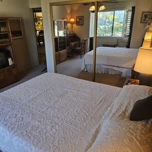 A bedroom with two beds, a desk, and a chair.