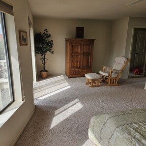 A room with a large window, a wooden cabinet, a chair, and a potted plant. - Waterfront Elegance with Steinway grand (Discovery Bay)