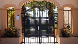 A gated entrance with a metal gate, arched doorway, and potted plants.