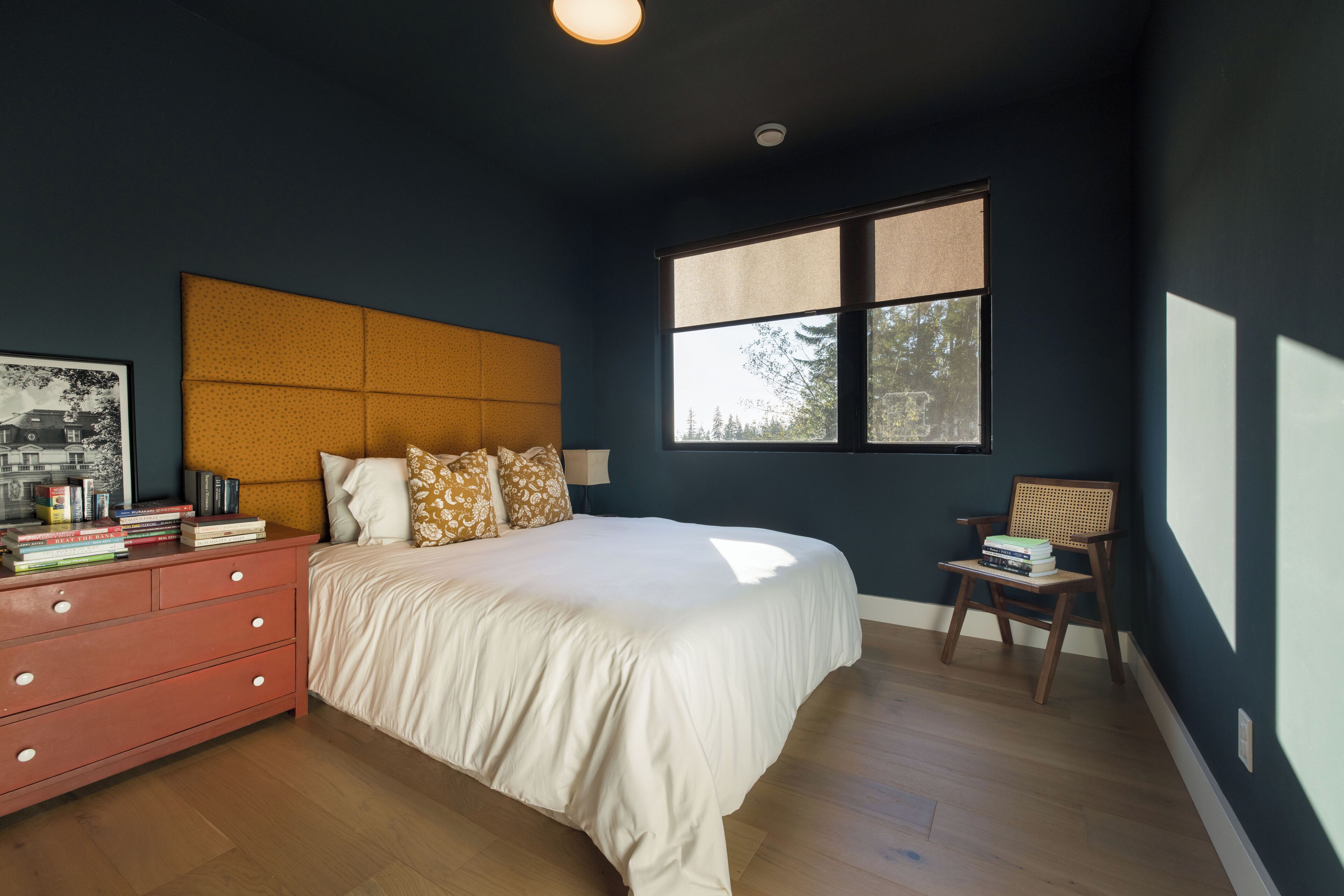 A bedroom with a bed, a dresser, a chair, and a window.