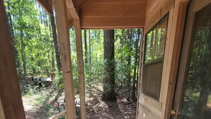 A wooden porch with a door leading to a forested area.