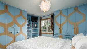 Een slaapkamer met een bed, kledingkast en een raam met gordijnen.