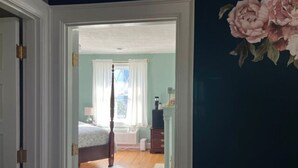 Une chambre à coucher avec un lit, une commode et une fenêtre avec des rideaux.