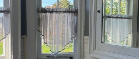 Un baño con ventana, inodoro y dispensador de toallas.