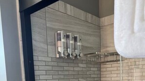 Une salle de bain moderne avec un espace douche, des murs carrelés et une porte en verre.