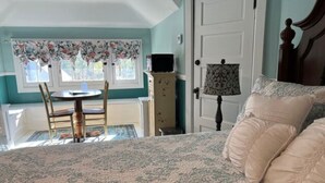 Un dormitorio con una cama, una silla, una mesa y una lámpara.