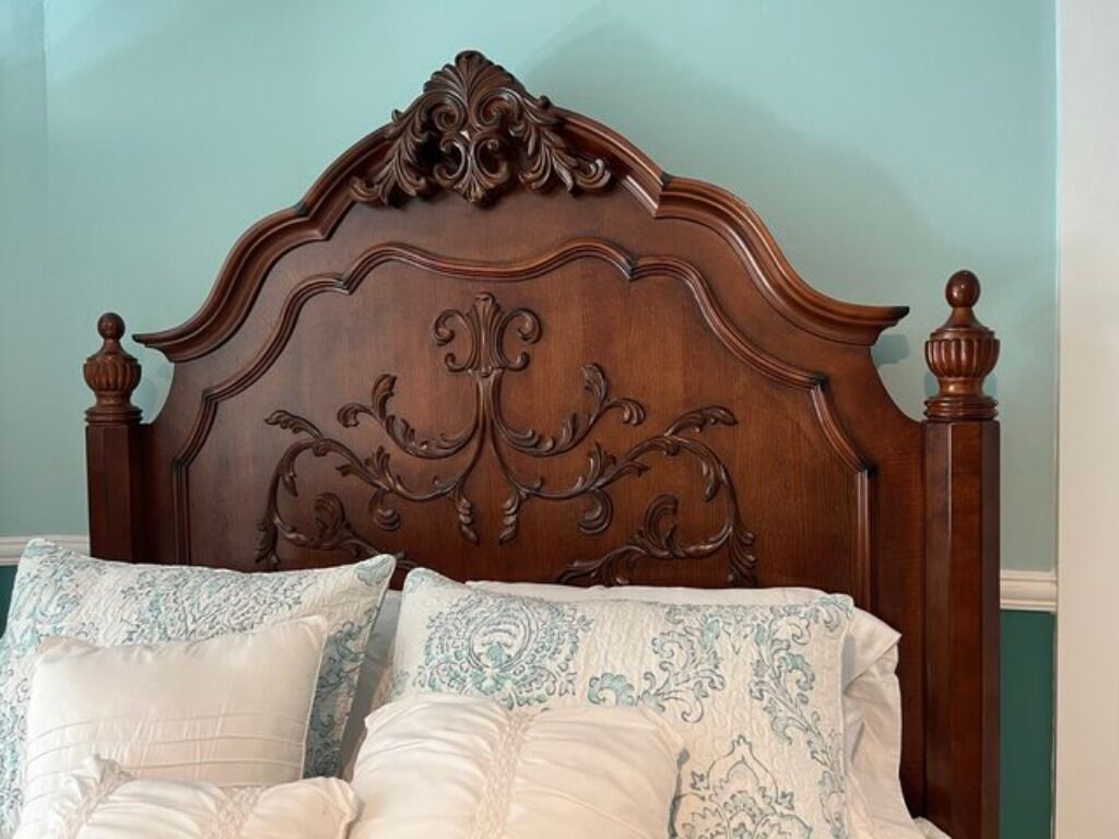 A bed with an ornate wooden headboard and decorative pillows.