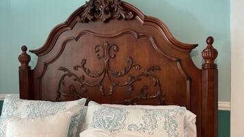 A bed with an ornate wooden headboard and decorative pillows.