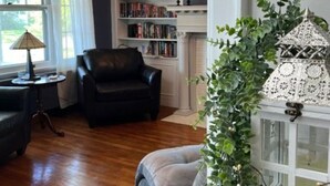 Un salón con chimenea, estanterías, un sillón de cuero, un sofá y una planta en maceta.