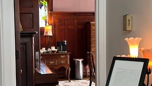 Una habitación acogedora con un piano, un escritorio con lámpara y un documento enmarcado sobre un atril.