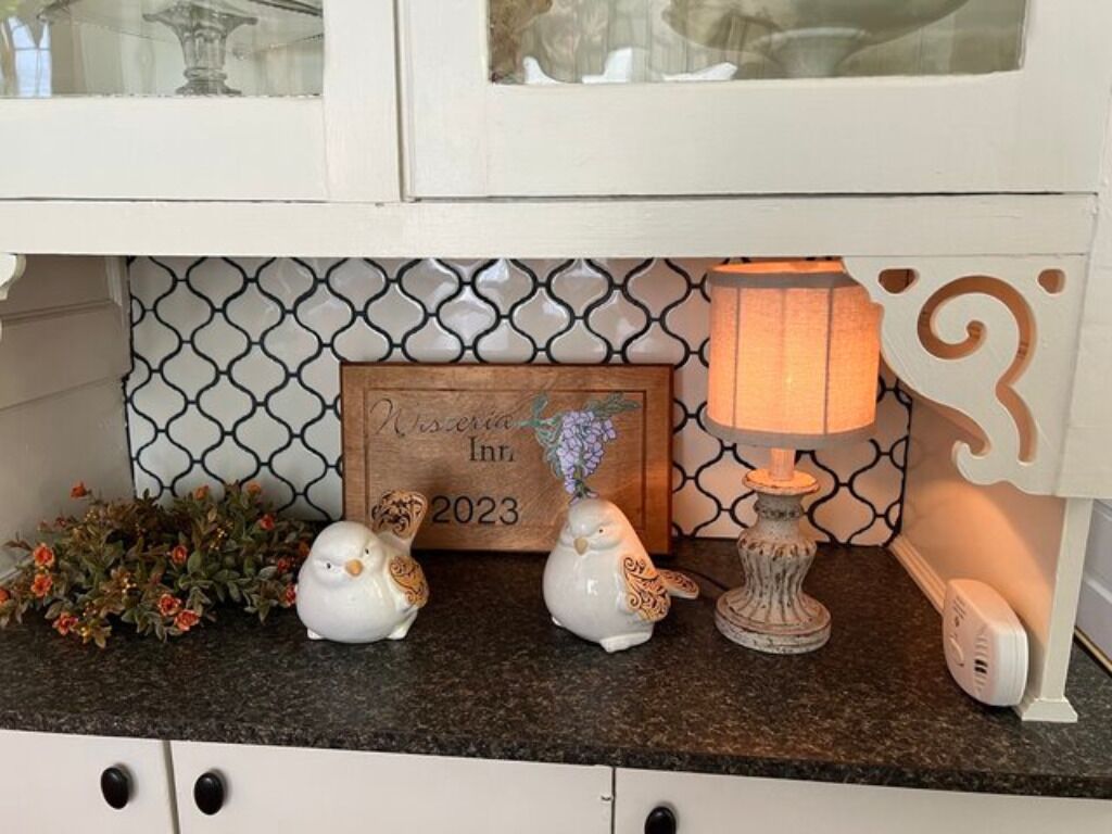 Een aanrecht met decoratieve objecten, een lijst met een bord en een lamp.