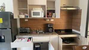 A compact kitchen with a microwave, toaster, coffee maker, and a sink.
