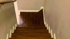 A wooden staircase with white trim and a handrail, leading to a landing with a door.