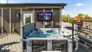 A hot tub on a rooftop deck with a mounted TV displaying streaming services. - The Highline - Downtown Rooftop Escape (Columbus)