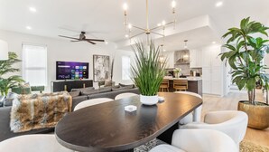 A modern living room with a dark wooden dining table, white sofas, and a large potted plant. - The Highline - Downtown Rooftop Escape (Columbus)