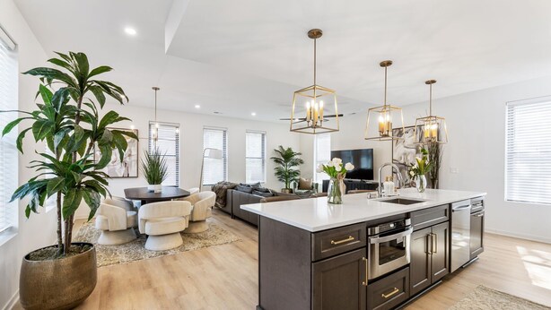 A modern kitchen with dark cabinetry, a large island, and pendant lighting. - The Highline - Downtown Rooftop Escape (Columbus)