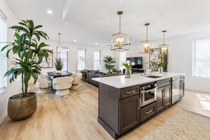 Una cocina moderna con armarios oscuros, una isla grande e iluminación colgante.