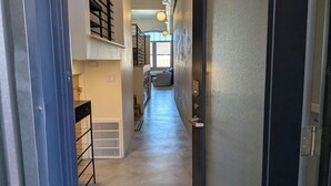 Ein schmaler Flur mit einer Treppe links, einem Heizkörper am Boden und einer Tür rechts.